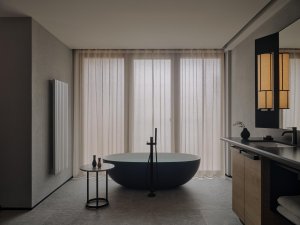 Aman Rosa Alpina Deluxe Suite – Badezimmer mit freistehender Badewanne und bodentiefen Vorhängen | nova-reisen