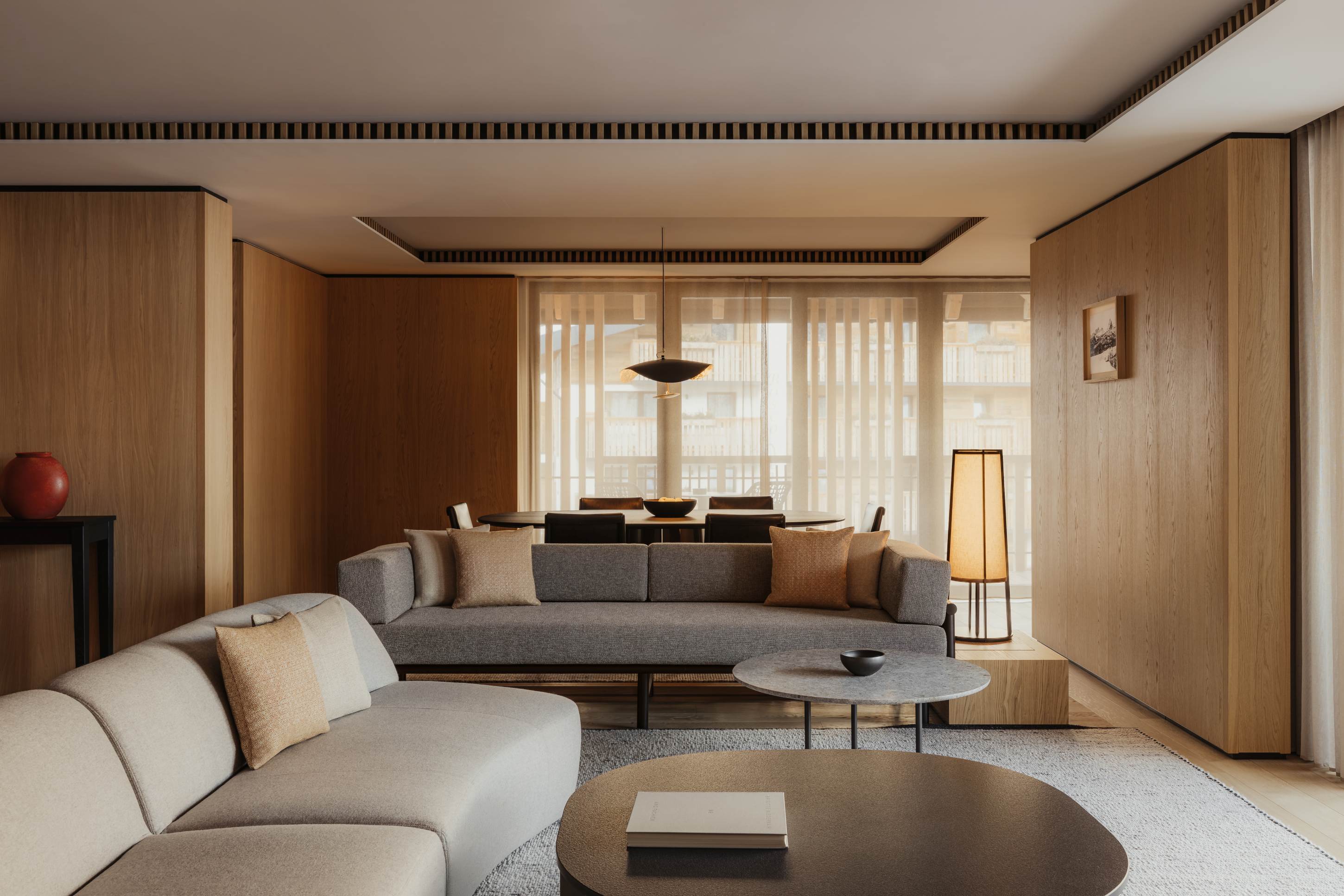 Aman Rosa Alpina Suite &ndash; stilvolle Lounge mit Sofa, Holzdetails und warmem Ambientelicht