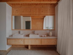 Aman Rosa Alpina Zeno Suite – Badezimmer mit Doppelwaschbecken, Holzdetails und Spiegel | nova-reisen