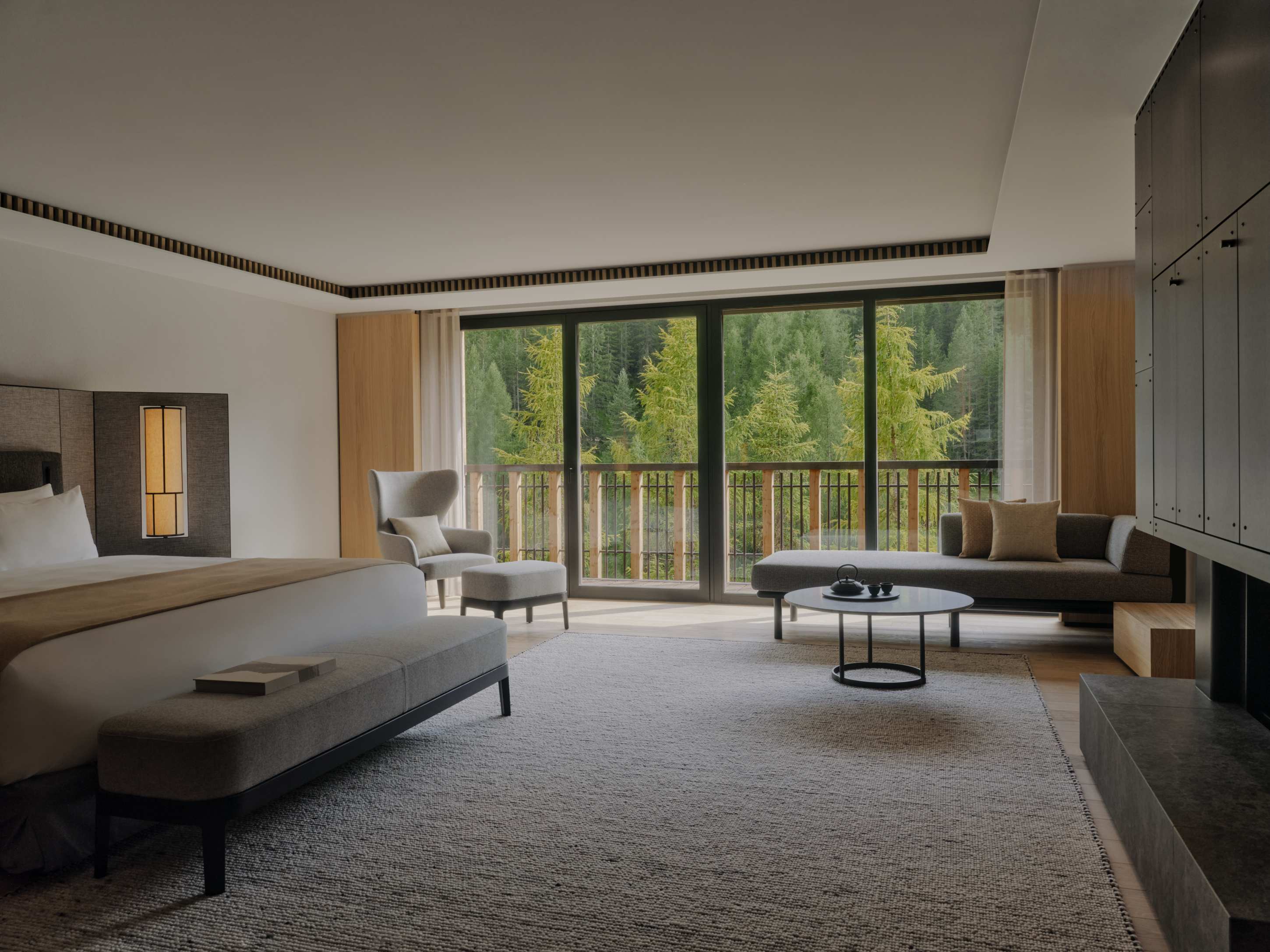 Aman Rosa Alpina Room – Zimmer mit Sofa, großem Fenster und Blick ins Grüne | nova-reisen
