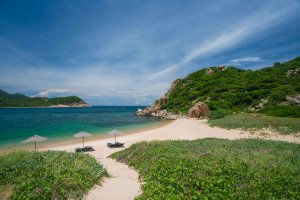 Amanoi Vietnam Private Beach – Weg durch tropische Vegetation zur ruhigen Bucht mit hellem Sand und türkisblauem Wasser | nova-reisen