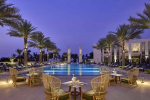 Eleganter Pool Bereich im Mandarin Oriental Muscat mit Blick auf das glitzernde Arabische Meer, umgeben von Palmen, luxuriösen Sonnenliegen und stilvoller Architektur – perfekter Ort zum Entspannen unter der Sonne Omans.