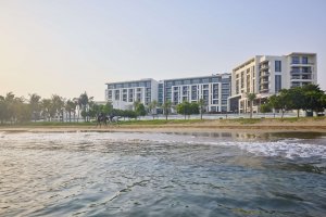 Außenansicht des Mandarin Oriental Muscat – beeindruckende Architektur im arabischen Stil, eingebettet zwischen Palmen und dem glitzernden Arabischen Meer, ein elegantes Wahrzeichen für Luxus und Gastfreundschaft in Oman.