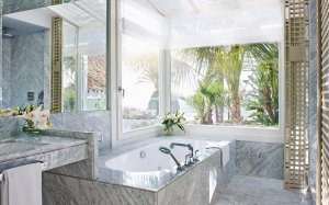 Helles Bad mit Blick nach draußen in den grünen mit Palmen bewachsenen Garten direkt von der Badewanne aus im Luxushotel Andalusien Marbella Club Hotel Golfresort & Spa Spanien 