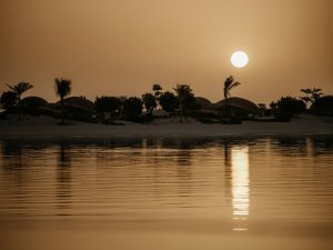 Sonnenuntergang über ruhiger Lagune im Luxusresort, goldene Spiegelung auf dem Wasser | Saudi-Arabien, Nujuma
