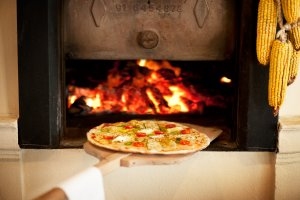 frische Pitzza wird in den Steinofen geschoben im Restaurant Caf Puente Horno im Luxusresort Marbella Puente Romano Beach Resort & Spa Spanien Andalusien