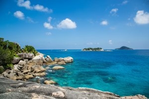 Ausblick über die Steinküste des Six Senses Zil Pasyon die ins saphirblaue Meer abfällt und Coco Island sowie die Schwesterinsel von Felicite Island im Indischen Ocean zeigt