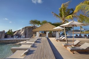 gemütliche Koko Bar direkt am Pool des Six Senses Pasyon mit Liegen und Daybeds in hellen Farben unter blauem Himmel und Palmen
