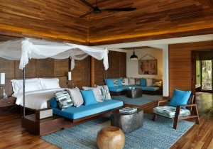 Schlafzimmer einer Pasyon Pool Villa in hellem Holz und türkisfarbenen Polstern mit Sofaecke im Six Senses Zil Pasyon