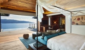 Schlafzimmer der Pool Villa im Six Senses Zil Pasyon mit hellen bis türkisfarbenen Farbtönen und Blick auf das saphirblaue Meer