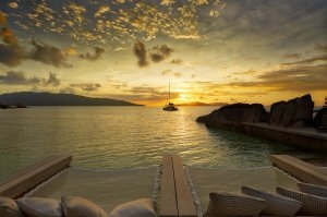 Sonnenuntergang in der Koko Bar mit Blick auf das goldfarbene Meer und die Nachbarinsel des Six Senses Zil Pasyon